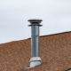 Metal Chimney On House Roof, Clean New Shiny Chimney Pipe On Blu