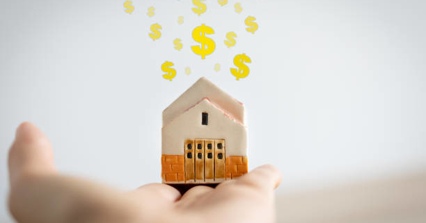 woman holding home model on hand with dollar signs above, investment concept
