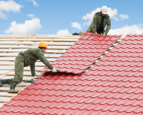 Rubber roofing - workers on roof at works with metal tile